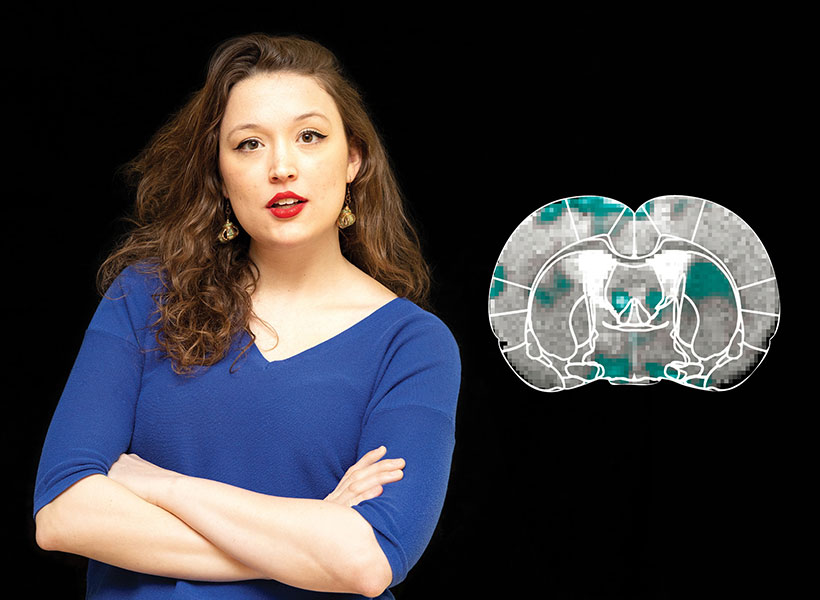 Scientist with folded arms next to a picture of a brain