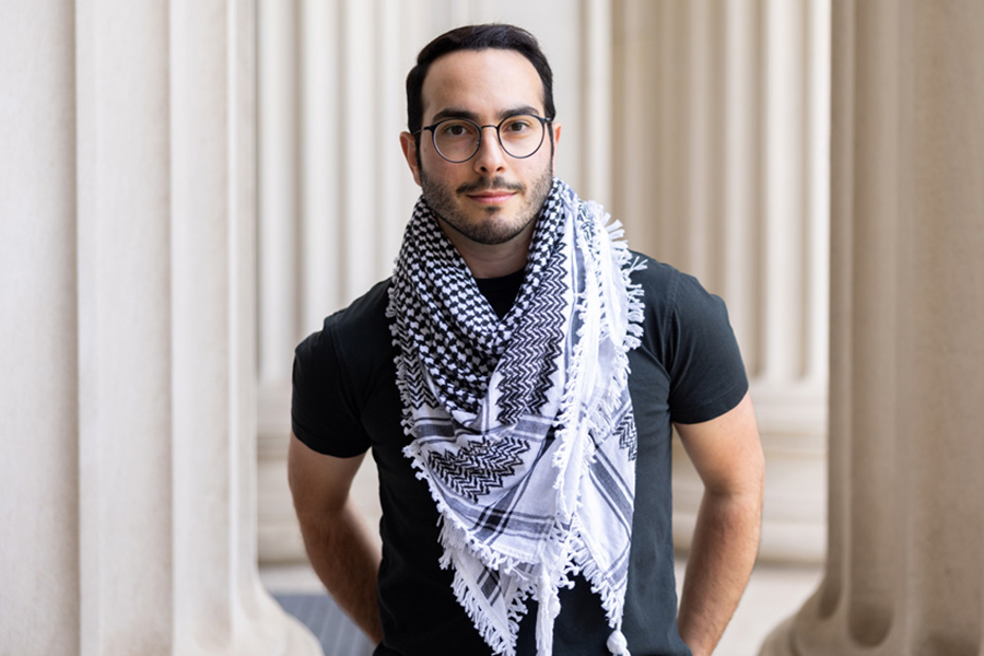 Ubadah Sabbagh stands among ivory pillars looking at camera.