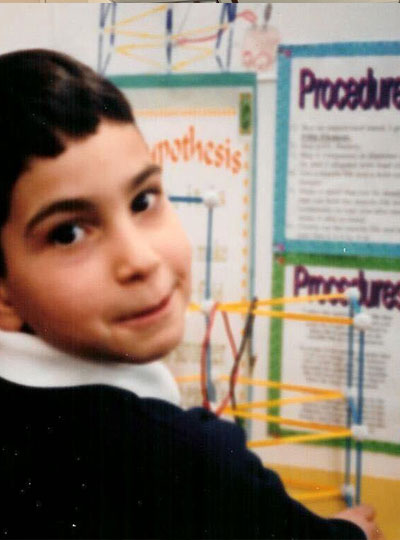 Child smiles in front of scientific poster.