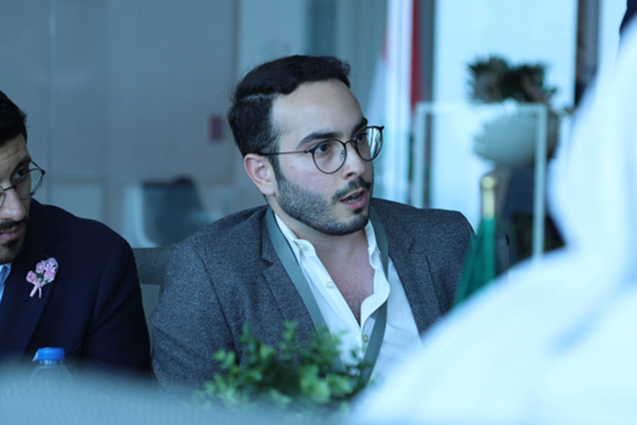 Profile of scientist Ubadah Sabbagh speaking at a table.