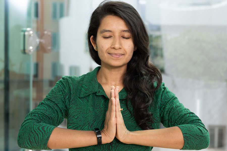 A woman with eyes closed and hands clasped in front of her body.