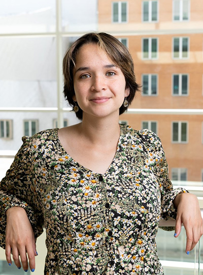 Portrait of a smiling woman leaning back against a railing. 