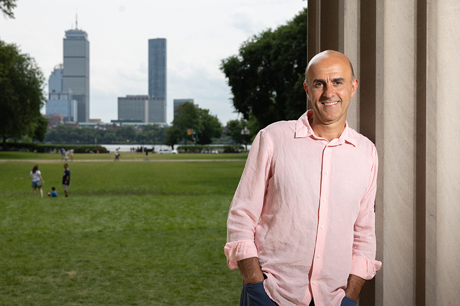 Man leaning against MIT column with Boston skyline in background.